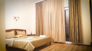 A bedroom with a bed, curtains, a nightstand, and a window. - Upstairs Hotel Tbilisi (Tbilisi)