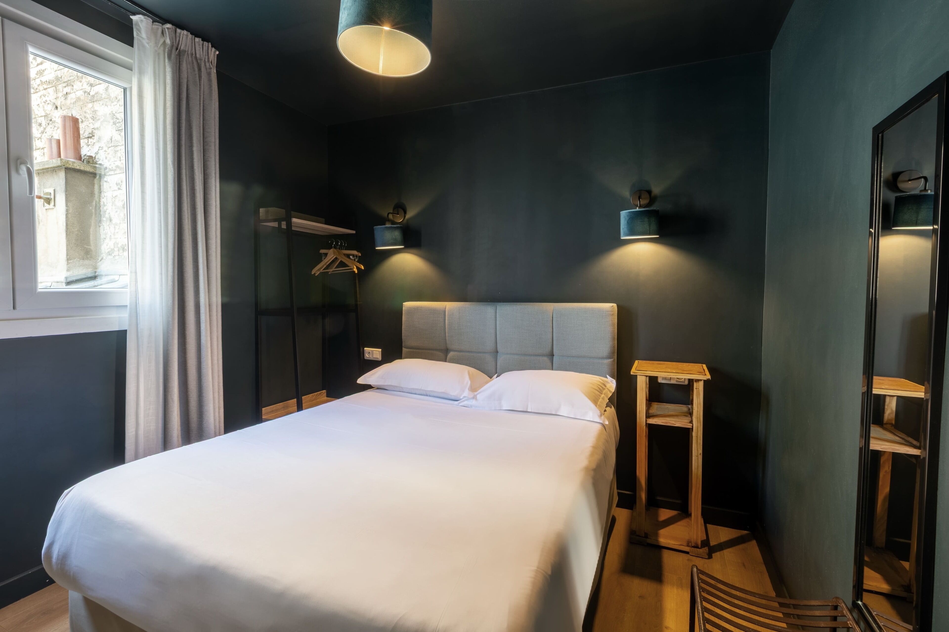 Un dormitorio moderno con una cama grande, mesitas de noche y una ventana con cortinas.