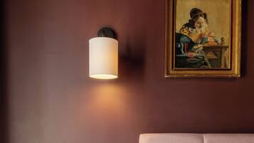 A bedroom with a bed, a nightstand, a lamp, and a painting on the wall.