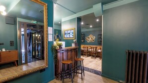 A bar area with stools, a large mirror, and a decorative wall piece. - HOTEL MAAT ETOILE (Paris)