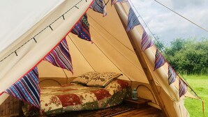 Ein Zelt mit einem Bett, ausgestattet mit bunten Decken und einer Laterne.