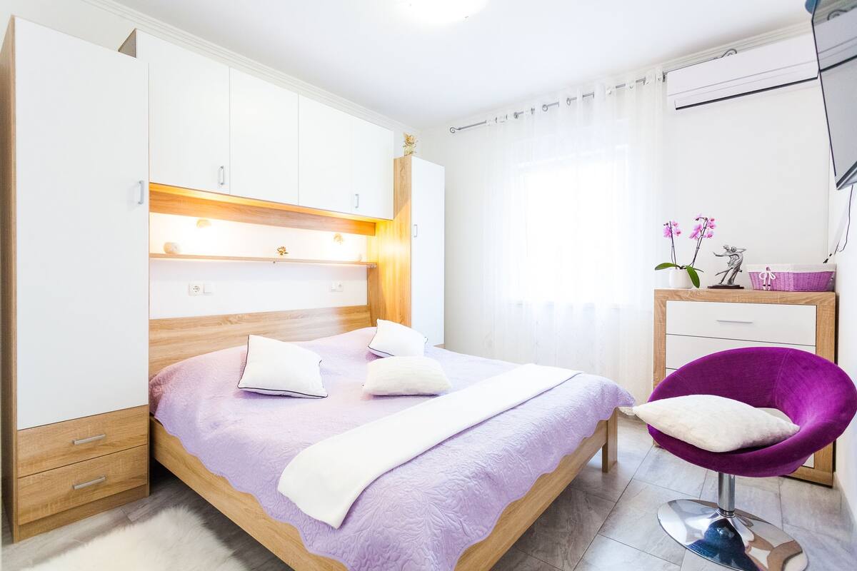 Um quarto com uma cama, uma cadeira, um guarda-roupa e uma escrivaninha.