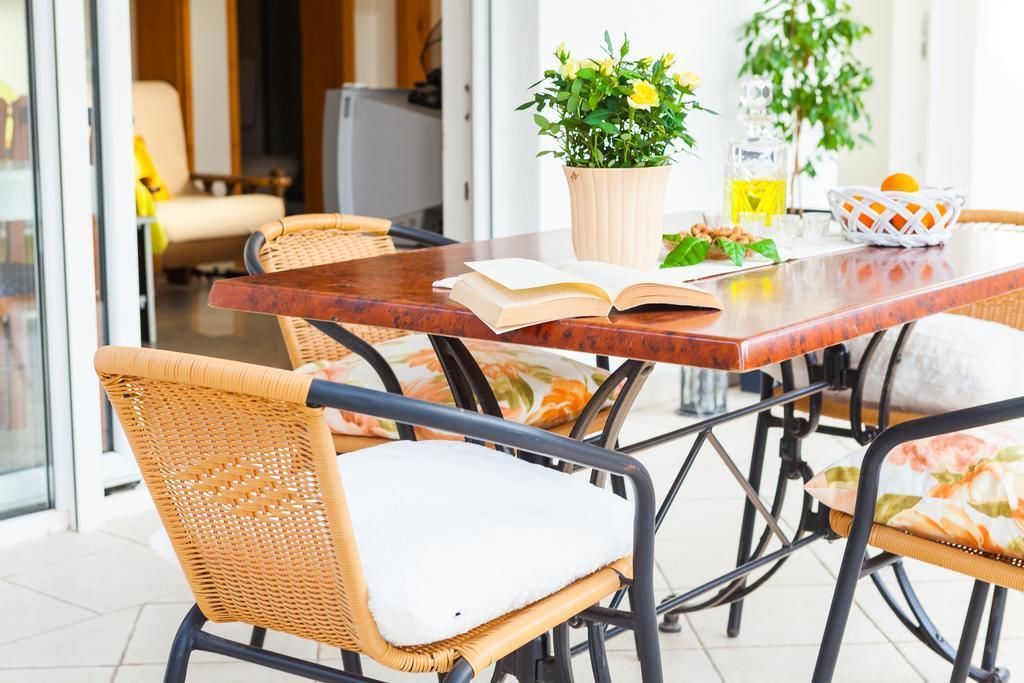 A dining area with wicker chairs, a wooden table, and a potted plant.