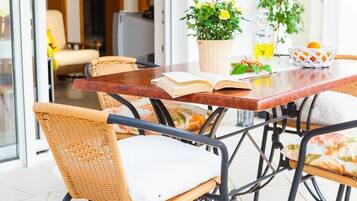 A dining area with wicker chairs, a wooden table, and a potted plant.