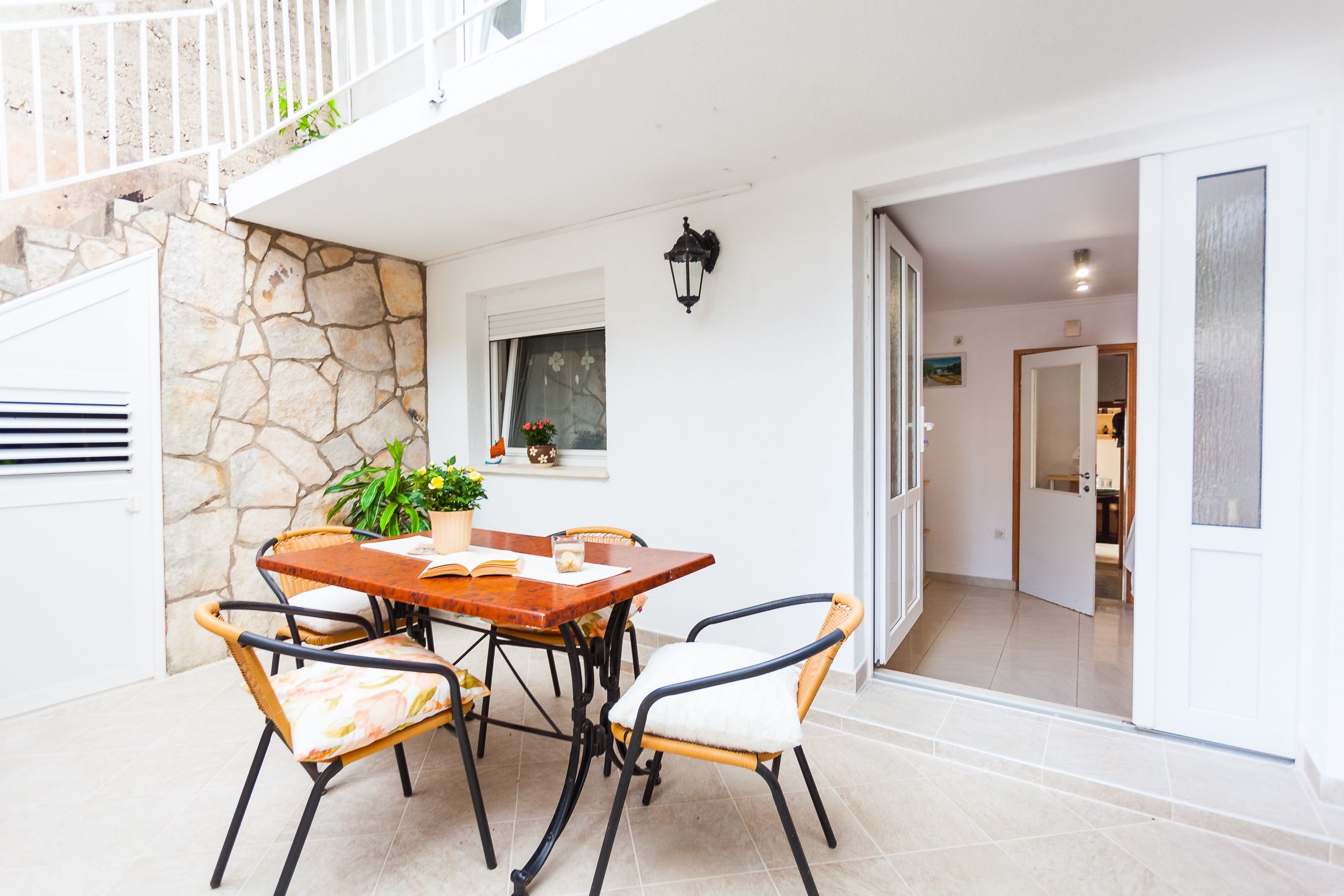 A dining area with a stone wall, a wooden table, and wicker chairs.