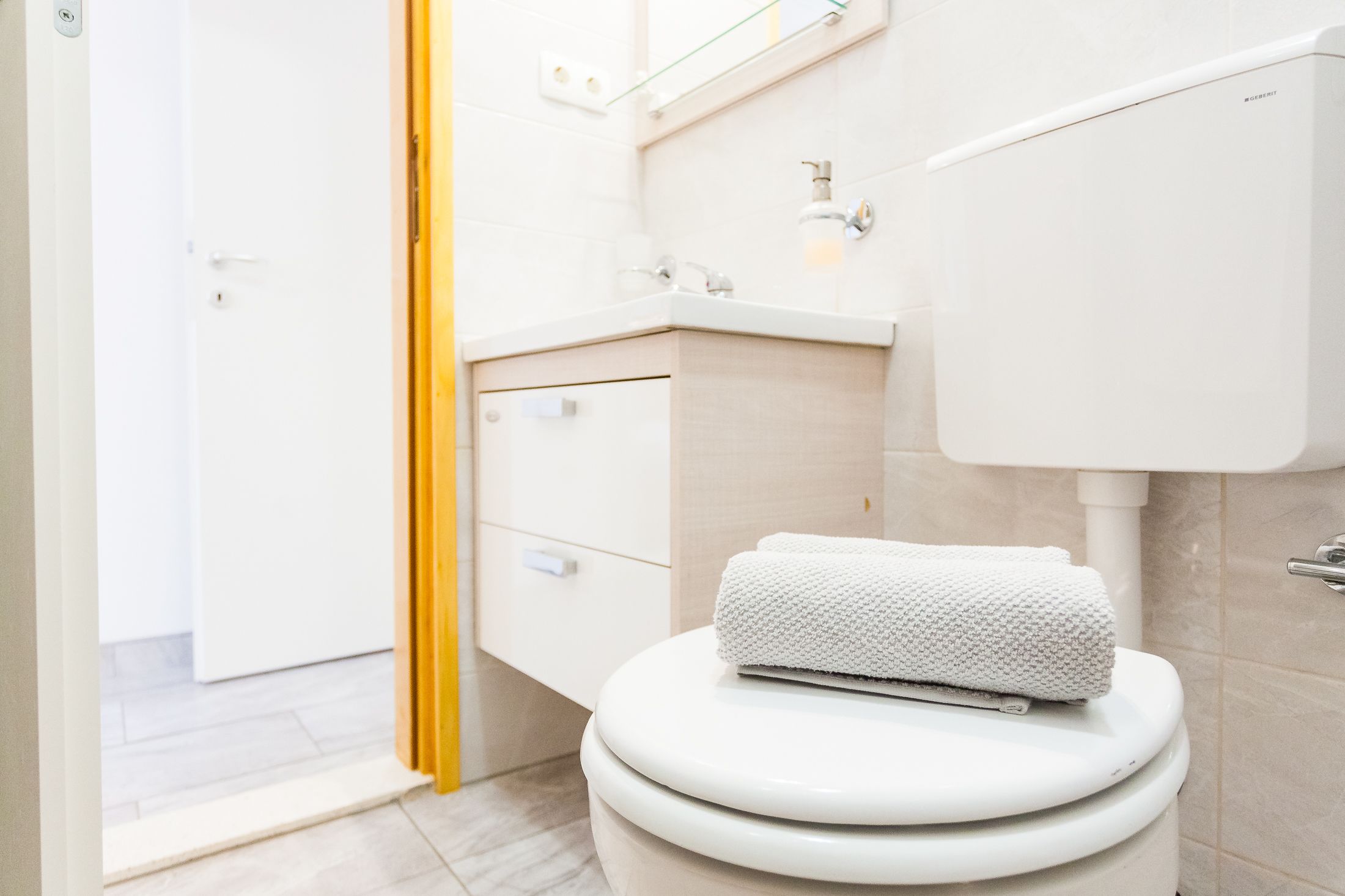 Ein modernes Badezimmer mit Toilette, Waschbecken und Spiegel.