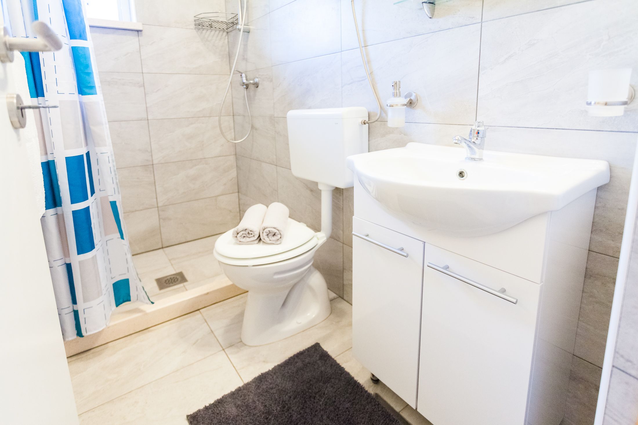 A modern bathroom with a white toilet, a sink, and a shower area.