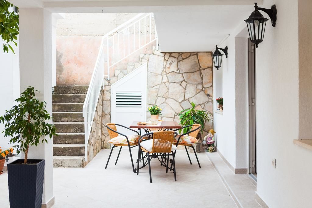 An outdoor patio with a stone wall, a staircase, and a dining area with wicker chairs and a table.