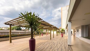 A covered outdoor area with a wooden floor, potted plants, and a pergola structure. - Alta Vista Thermas Resort (Caldas Novas)