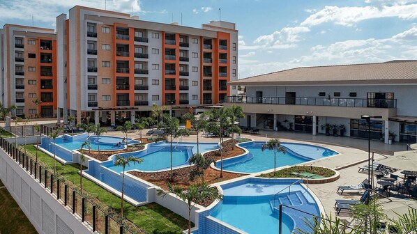 Un hôtel doté de plusieurs piscines, d’un espace extérieur couvert et d’un bâtiment à plusieurs étages avec des balcons.
