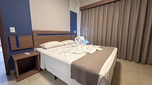 A hotel room with a bed, a bedside table, a lamp, and a window with curtains. - Alta Vista Thermas Resort (Caldas Novas)