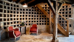 A rustic room with a stone wall, wooden staircase, and two red upholstered chairs.