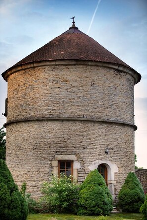 Une tour de pierre surmontée d’un toit conique, avec une petite fenêtre en arc de cercle et une cloche au sommet.