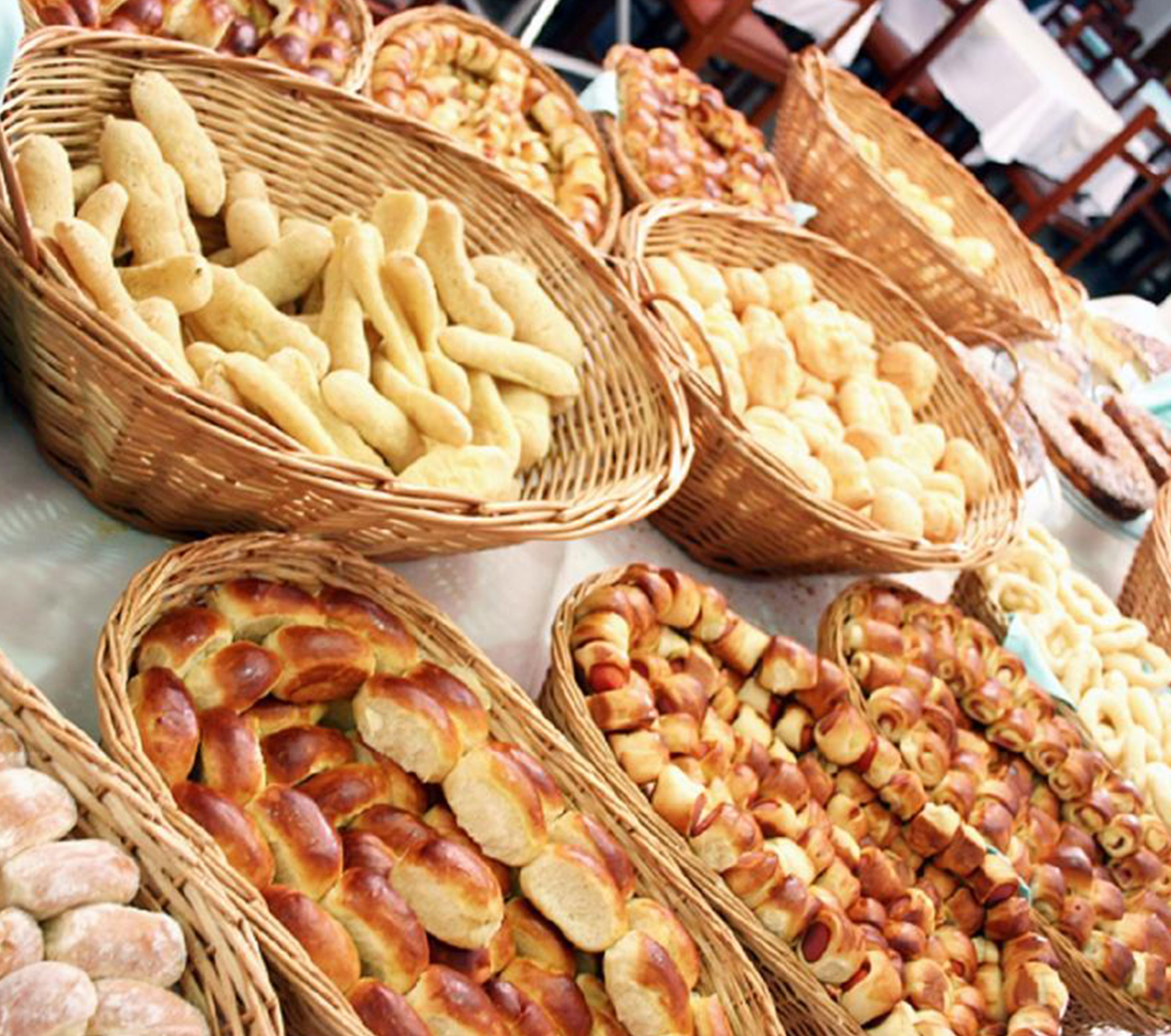 A variety of bread and pastries displayed in wicker baskets.