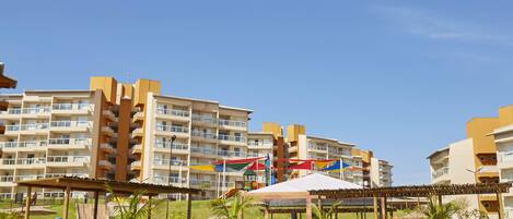 A hotel with multiple floors, outdoor seating areas, and a pool.