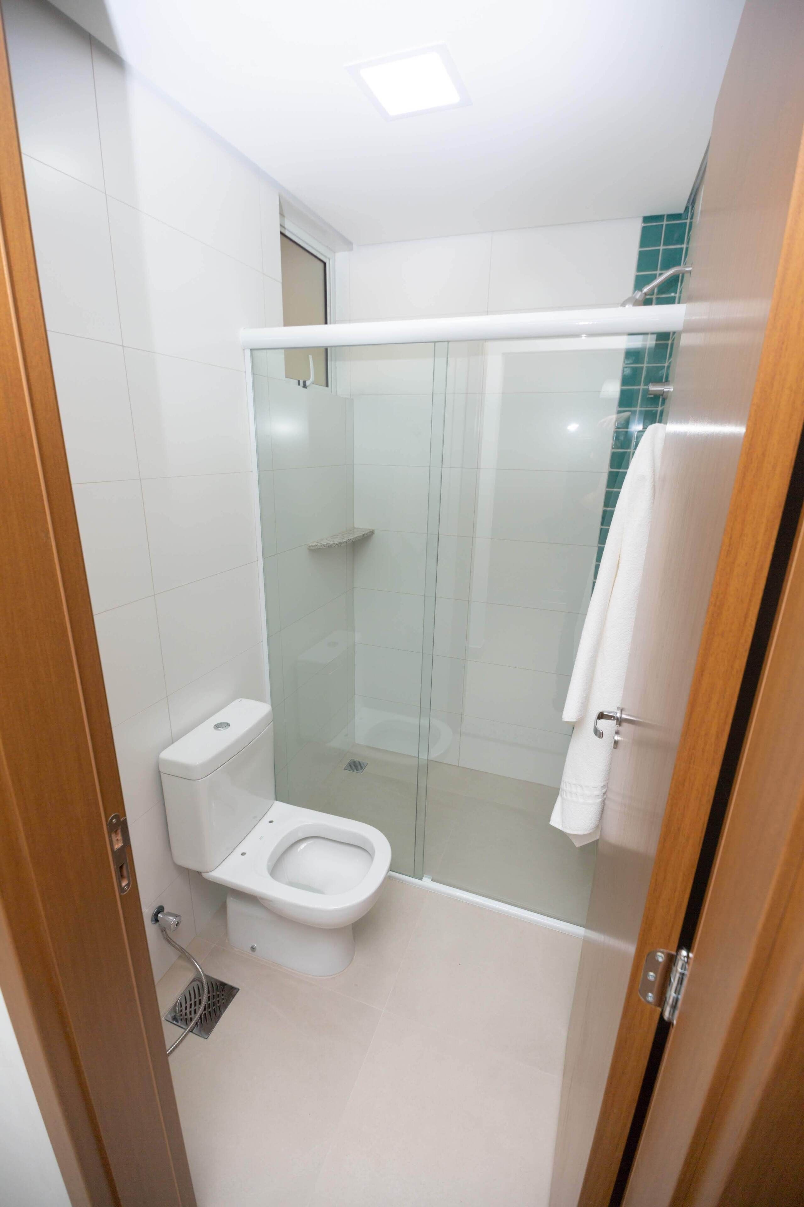 A modern bathroom with a glass-enclosed shower, a toilet, and a towel rack.