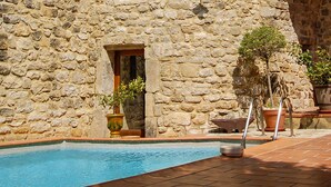 Un edificio in pietra con piscina e piante in vaso.