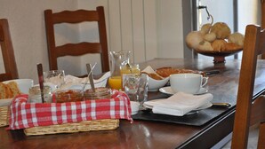 Una tavola imbandita per la colazione, con pane, pasticcini, un bicchiere di succo d'arancia e una tazza di caffè.