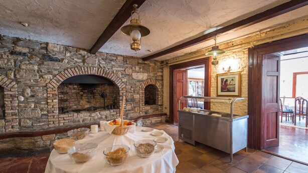 A stone fireplace, a buffet table with food and drinks, and a metal buffet station.
