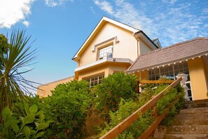 A two-story house with a yellow facade, a balcony, and a staircase leading up to the entrance. - Greenway Manor Hotel (Waterford)
