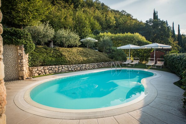 Una piscina al aire libre de temporada, sombrillas