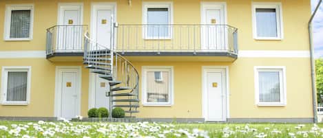 Ein gelbes Gebäude mit Wendeltreppe, zahlreichen Fenstern und einem Balkon.