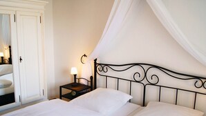 A neatly made bed with white linens, a bedside table with a lamp, and a wardrobe with a mirror. - Appartementhaus Gutenberg - Für Paare, Freundinnen & Freunde, Alleinreisende - Parkplatz & WLAN - 2 Min zum See, 6 Min zum Strand (Binz)
