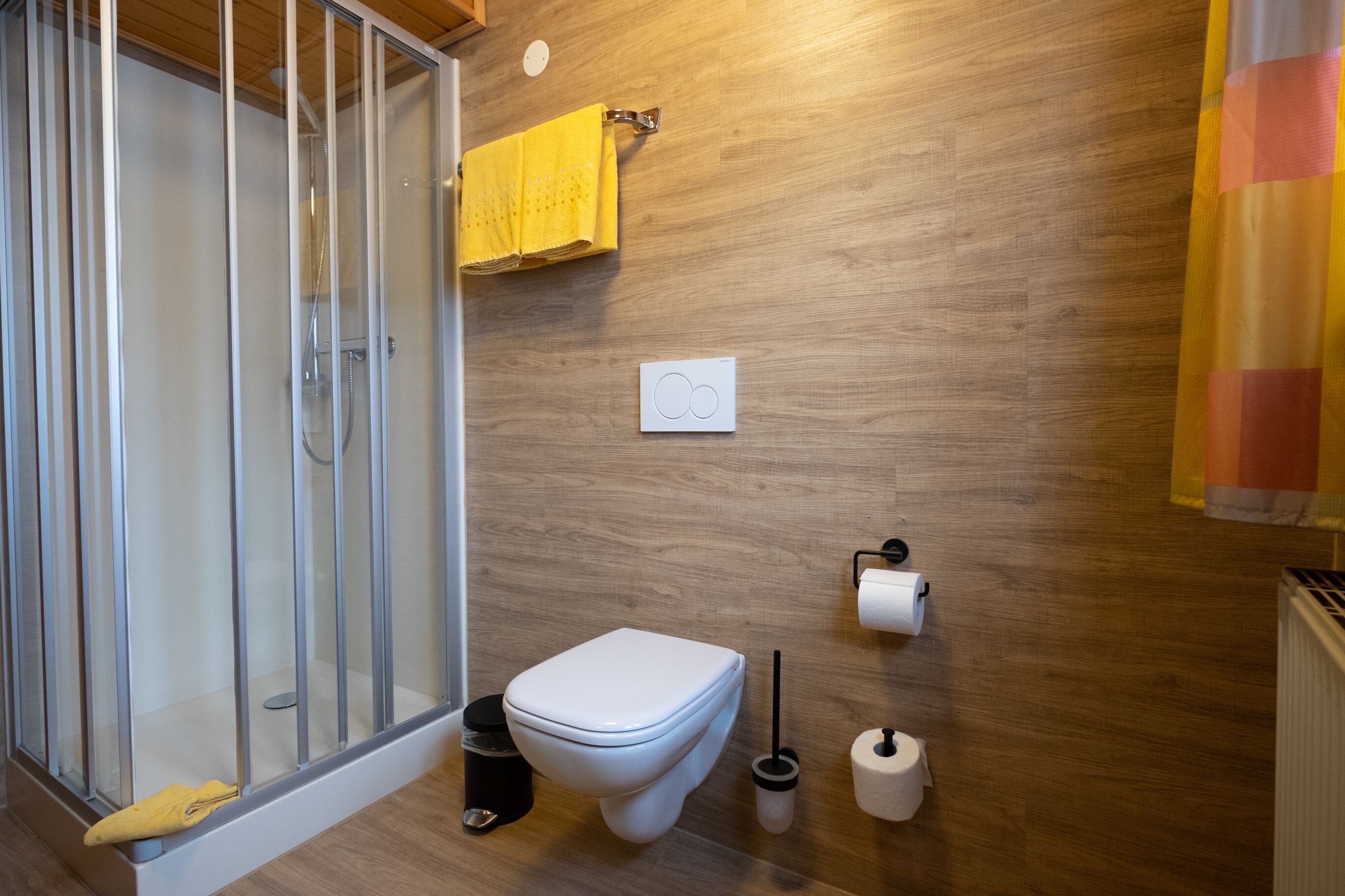 Une salle de bain avec douche, toilettes et porte-serviettes.