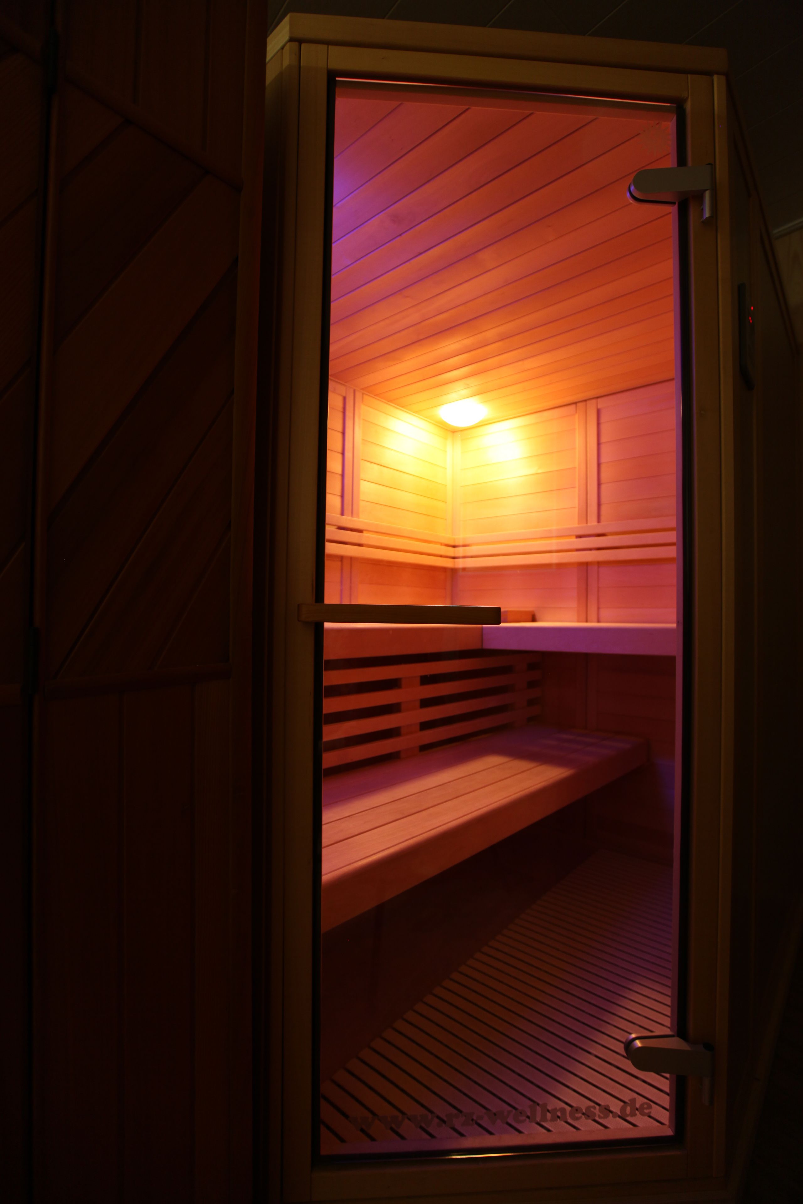 Eine Sauna mit Holzbänken und einer Glastür.
