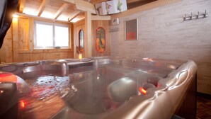 Interior de madera con una bañera de hidromasaje, vigas de madera y una ventana.
