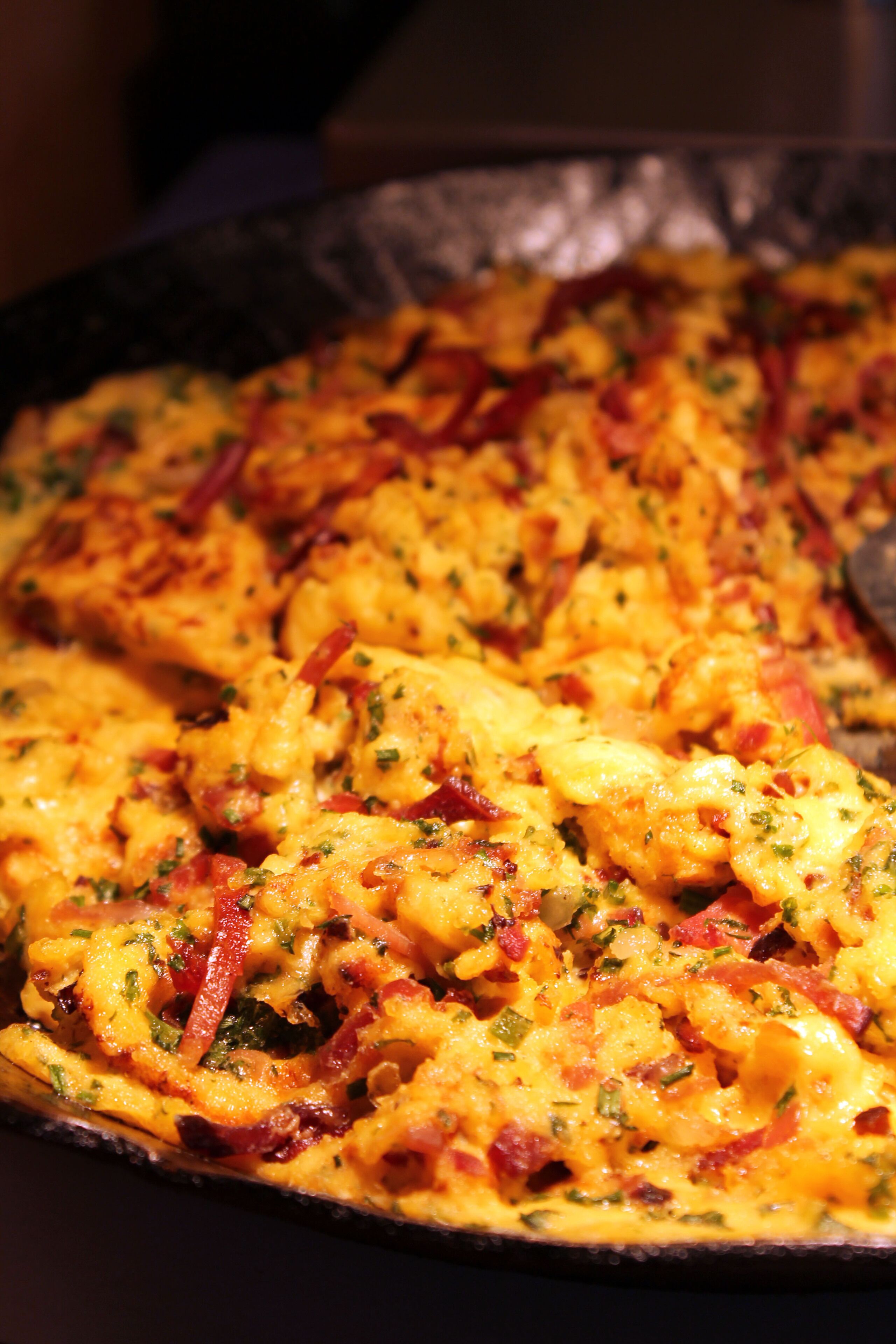 A close-up of a dish with melted cheese, red peppers, and herbs.