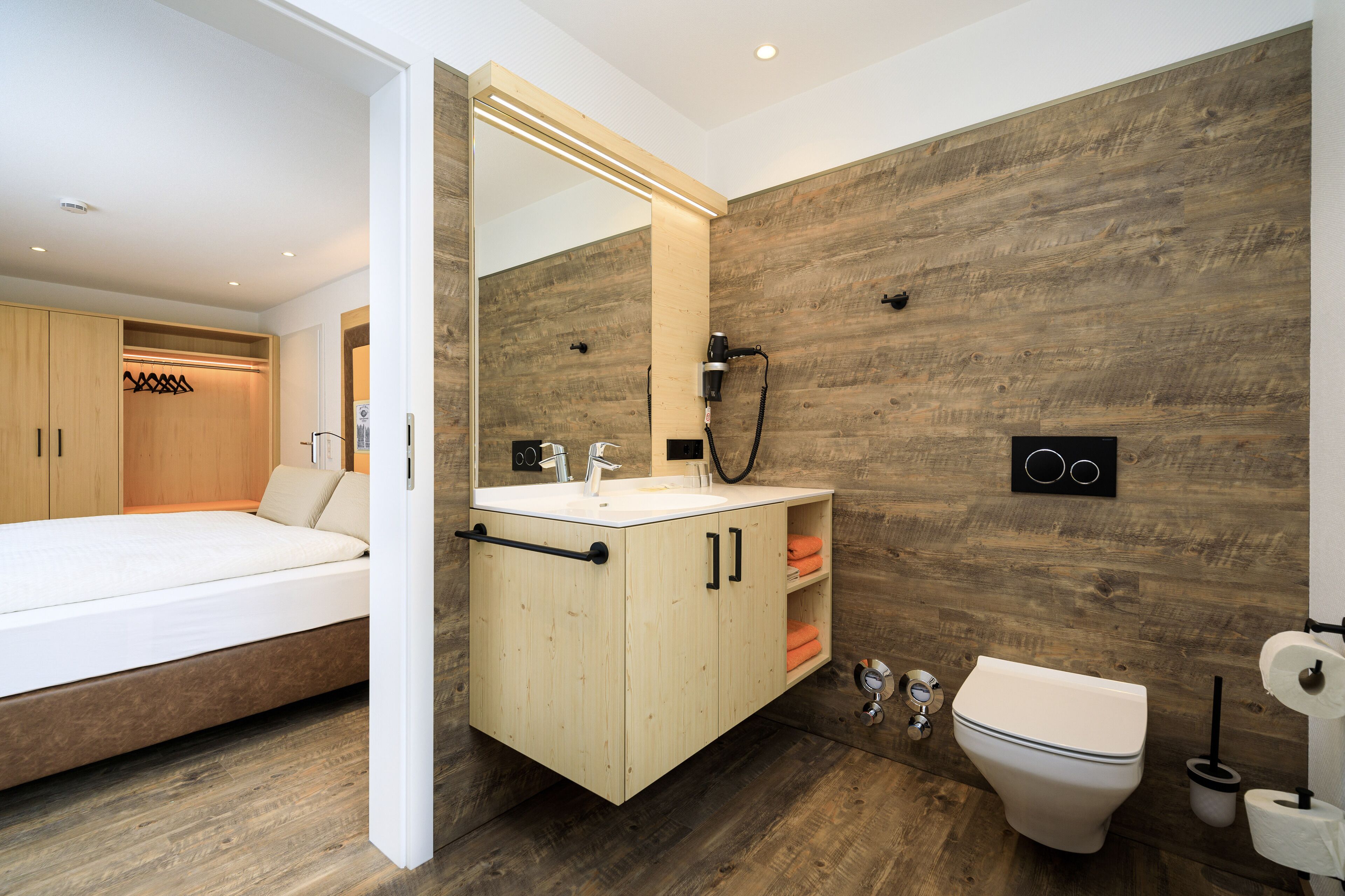 Un baño moderno con pared de madera, un lavabo blanco y un inodoro.