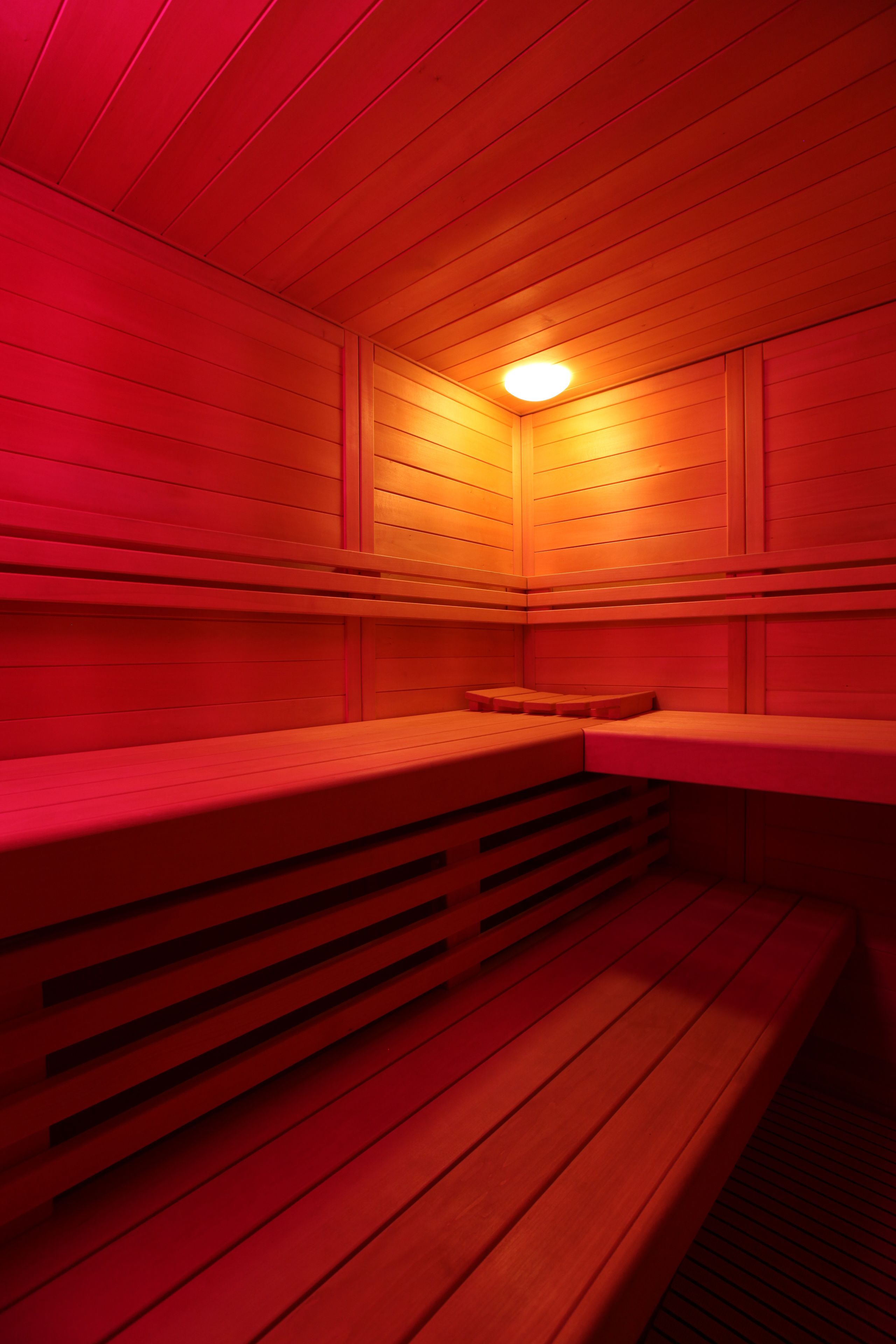 Een sauna met houten banken en een schuin vloerontwerp.