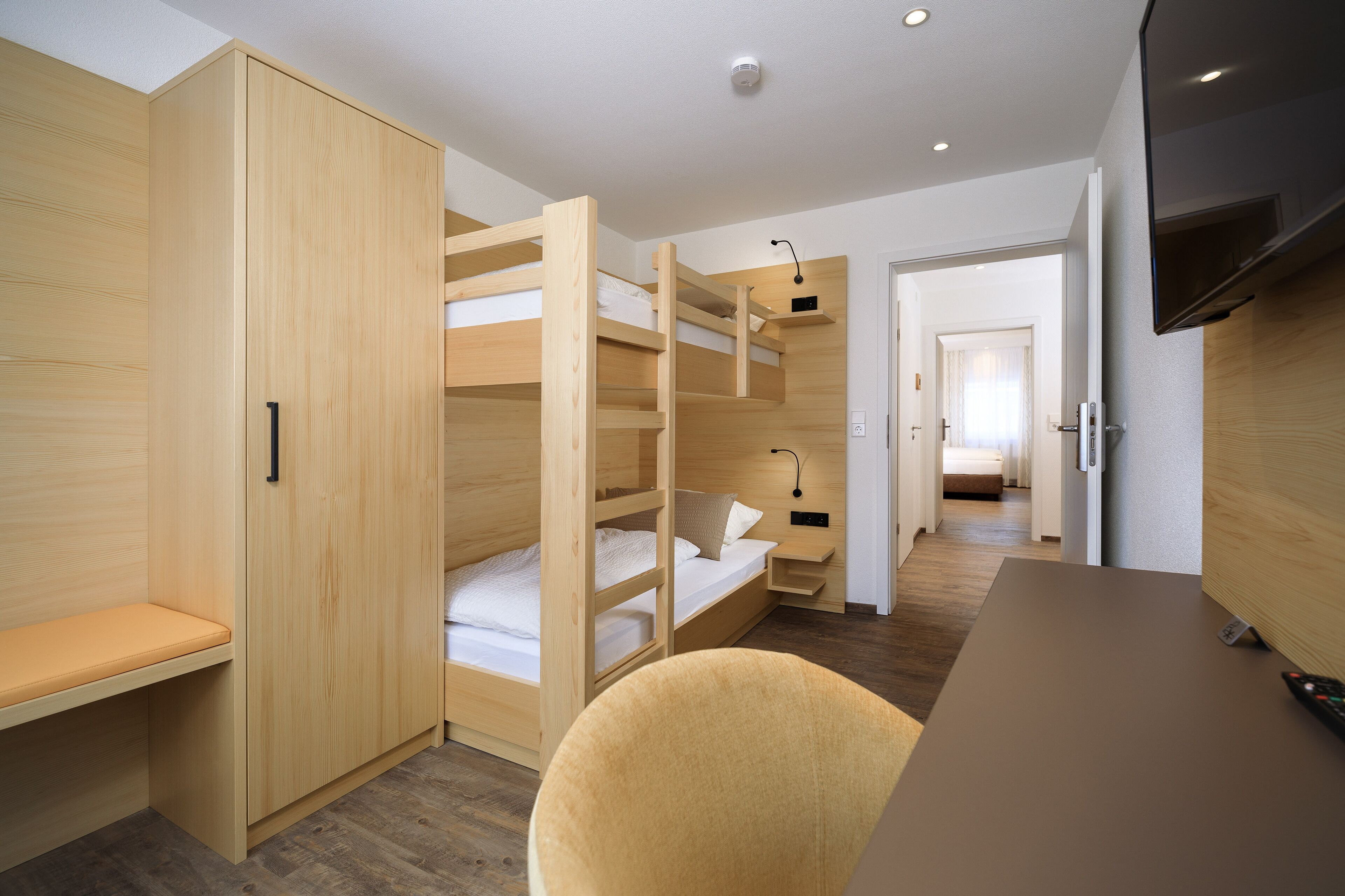 A compact room with a bunk bed, a desk, and a chair.