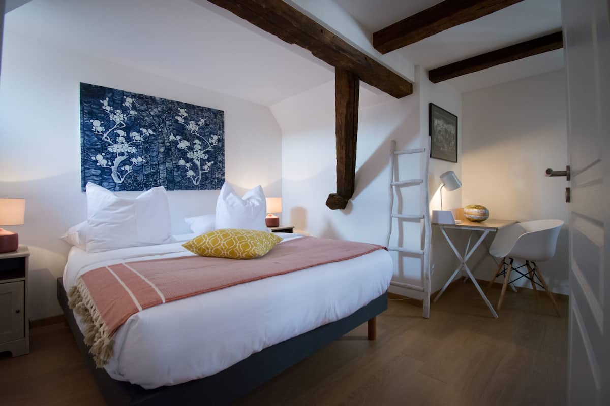 Een slaapkamer met een bed, nachtkastjes, een bureau en een stoel.
