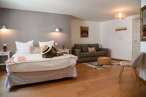Un dormitorio con cama, mesitas de noche, un sofá, una silla y una lámpara fijada en la pared.
