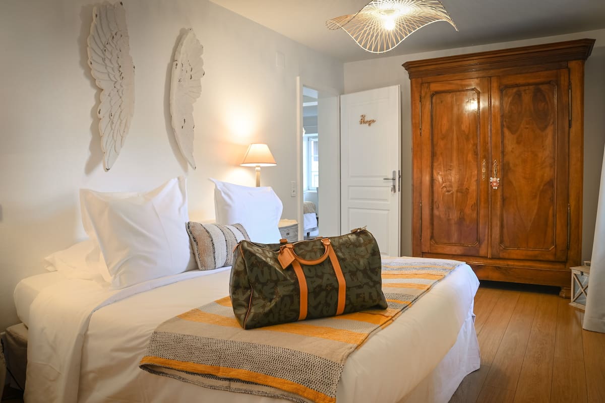 Een slaapkamer met een bed, kussens, een lamp, een kledingkast en een decoratief wandobject.