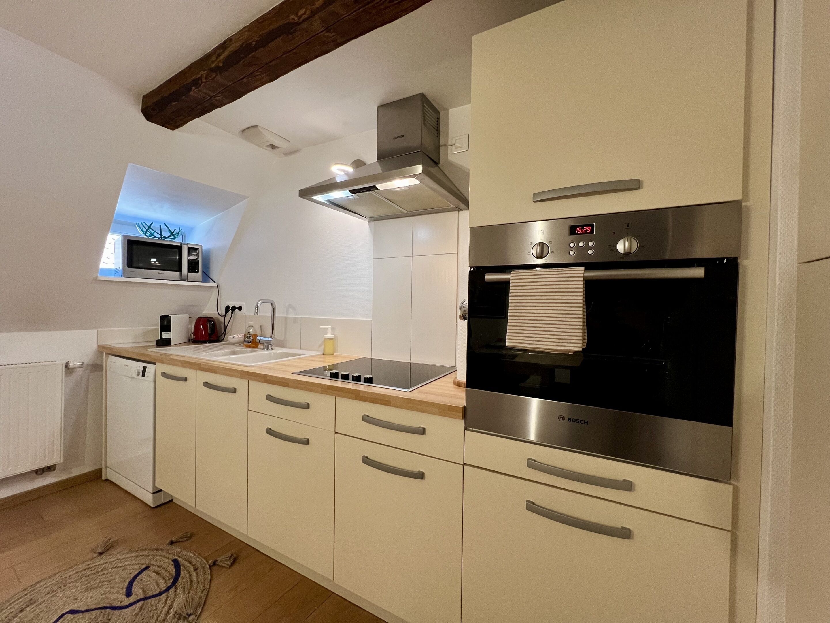 Een moderne keuken met een magnetron, fornuis, oven en een raam boven de gootsteen.