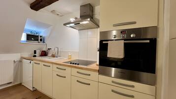 Een moderne keuken met een magnetron, fornuis, oven en een raam boven de gootsteen.