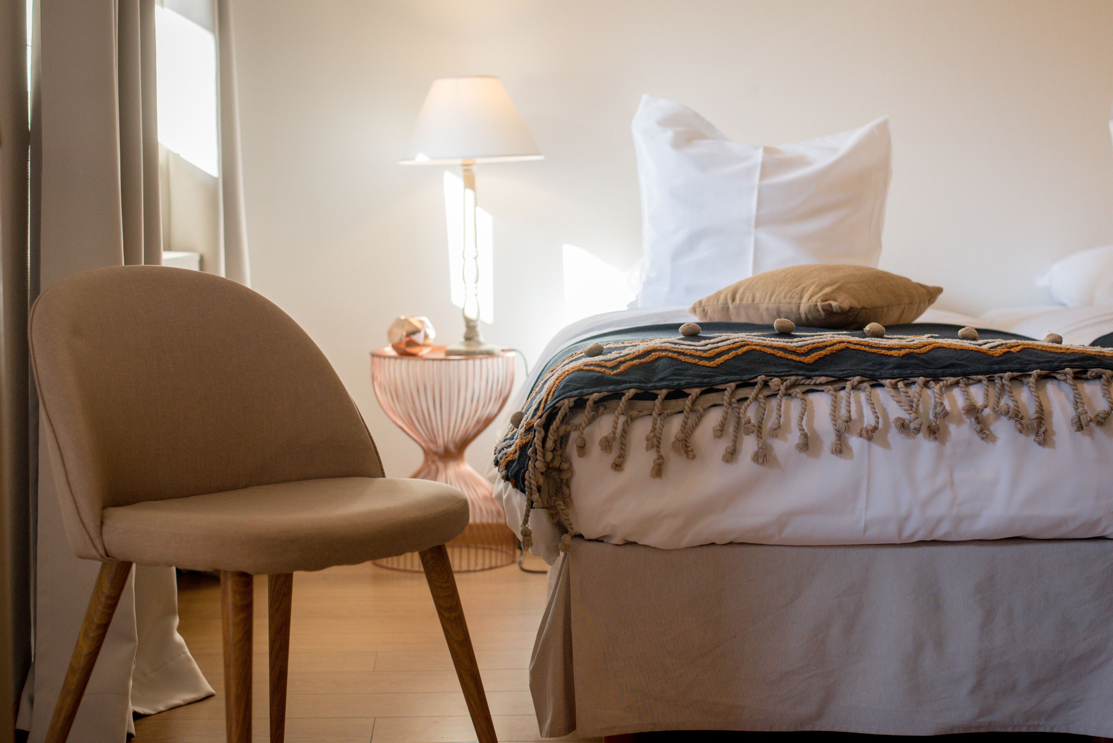 A bedroom with a bed, a chair, a lamp, and a small table.