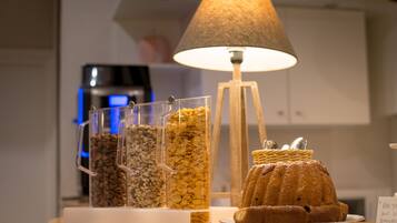A breakfast display with cereal containers, a lamp, and a bundt cake on a table.