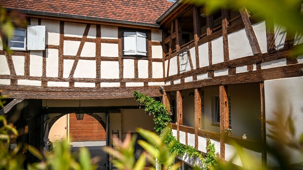 A traditional half-timbered house with a covered walkway and a wooden door. - Hameau D'eguisheim (Eguisheim)