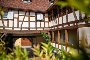 Une maison traditionnelle à colombages, dotée d’une galerie couverte et d’une porte en bois.