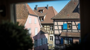 A traditional European town with half-timbered houses and a pink building with white shutters. - Hameau D'eguisheim (Eguisheim)