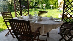 A round table set for four with a lace tablecloth, surrounded by wooden chairs. - B&B All'Aeroporto (Curtatone)