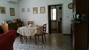 A dining area with a table set for four, a red armchair, and a patterned floor. - B&B All'Aeroporto (Curtatone)
