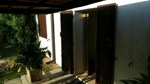 An open doorway leading to a covered outdoor area with a potted plant and a concrete step. - B&B All'Aeroporto (Curtatone)