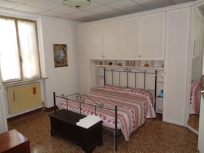 A bedroom with a bed, a small table, and built-in storage cabinets.