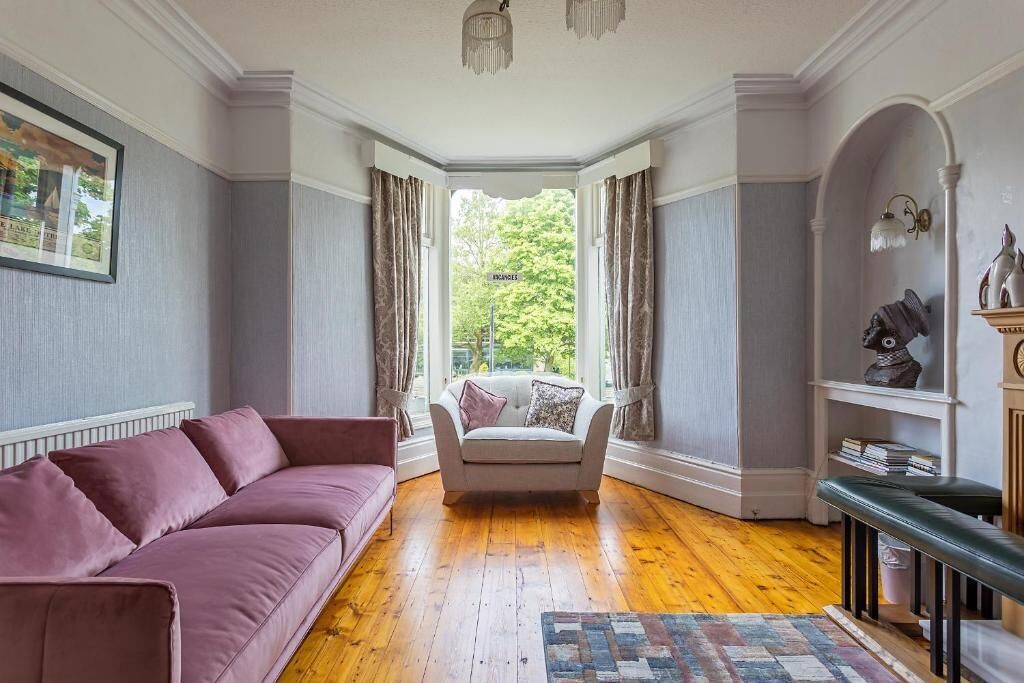 A room with a large window, a sofa, a chair, and a bench.