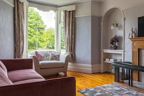 A living room with a sofa, a bench, a fireplace, and a view of the outdoors. - GLENHOLME Kendal (Kendal)